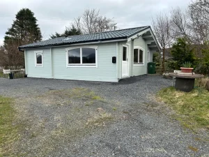 Wide log home with light exterior and gravel driveway